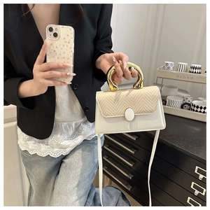 Detail of white leather handbag with straw woven lid and golden horseshoe handle