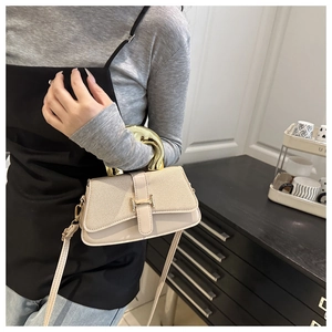 Close-up of small square bag with textured fabric, leather and gold H-buckle detailing