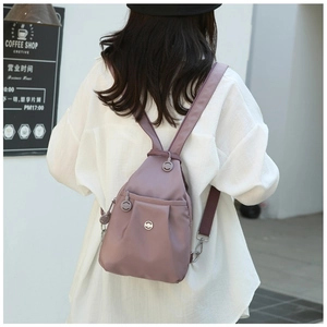 Lilac mini backpack in waterproof oxford fabric shown on a model in a casual setting