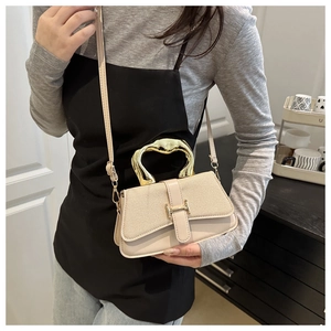 Detail view of stylish crossbody bag featuring gold H-shaped clasp and unique metal handle