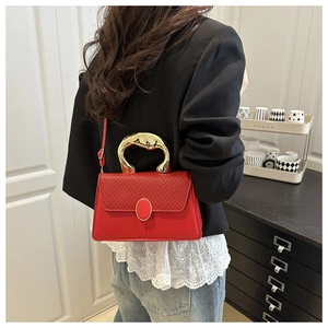 Chic red shoulder bag with woven flap detail and unique gold metallic handle