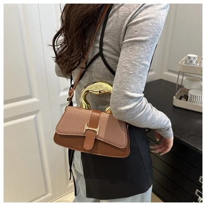 Detailed side view of two-tone brown tote bag featuring golden H-shaped metal buckle