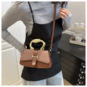 Detail of a brown patchwork handbag with a golden H buckle and textured woven flap cover
