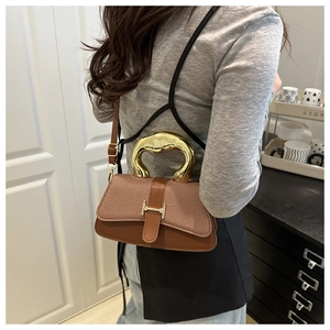 Macro view of textured brown fabric and leather handbag with irregular gold metal handle