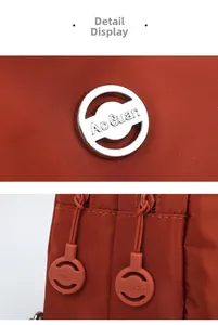 Close-up of orange nylon mini backpack showing metal logo and plastic zippers detail