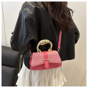 Detail view of pink crossbody bag with abstract gold handle and H-shaped metal clasp buckle