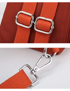 Close-up of polished silver metal hooks and adjustable strap buckles on orange nylon bag