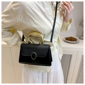Detail of lizard texture leather and artistic gold geometric handle on black crossbody bag