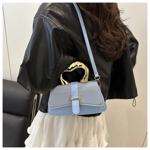 Detail of light blue square bag with gold H-buckle and metal handle on a model