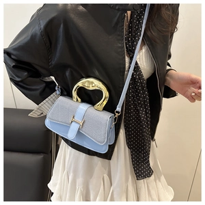 Detail of light blue box bag with woven flap and gold H buckle being held by model