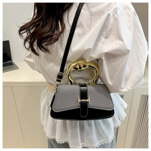 Detail showing the wide golden metal handle and adjustable strap on the contrast shoulder bag