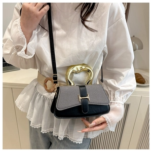 Close-up of contrast square bag with grey twill flap, black leather and gold H-clasp