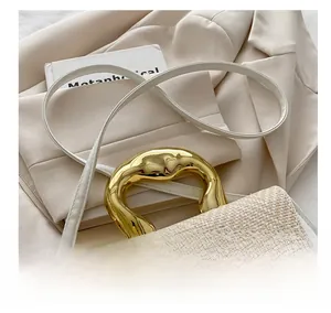 Detail of elegant woven crossbody bag with wavy gold metal handle and slim shoulder strap