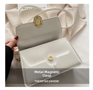 Detail of the high-quality gold magnetic snap closure on a white leather crossbody bag