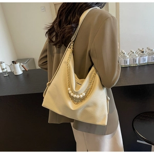 Close-up of off-white tote bag with elegant pearl charms and gold chain details
