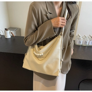 Detail of cream white leather tote bag with pearl and gold chain strap decoration