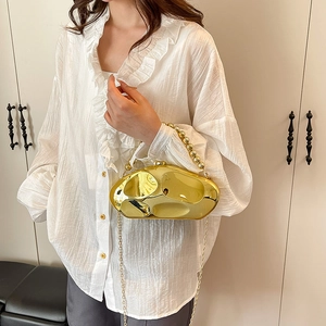 Clutch in metallo dorato con manico a perle e catena indossata da una modella