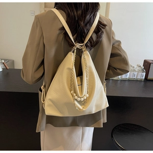 Detail view of cream white leather backpack with elegant pearl and gold chain charms