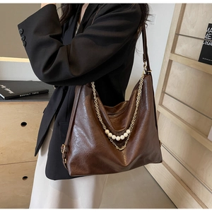 Détail du sac cabas en cuir marron foncé avec chaîne dorée et sangle en perles