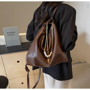 Détail du sac cabas marron foncé avec chaîne en perles et texture cirée sur modèle