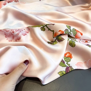 Detailed macro shot of vintage floral print silk scarf with pink satin fabric texture
