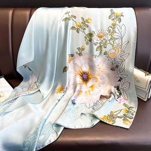 Detail of light blue silk scarf with floral peony pattern draped on a leather sofa