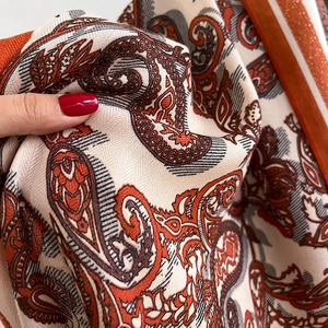 Close-up of premium silk scarf featuring intricate paisley patterns and twill weave texture