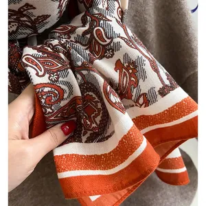 Detail of vintage paisley pattern fabric on a beige scarf with orange striped border