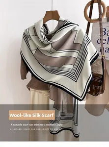 Detail of soft geometric patterned scarf in beige and brown hanging on a wooden hanger