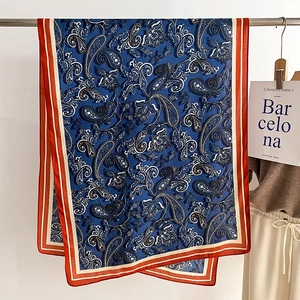 Detailed macro view of silk texture with deep blue paisley print and orange border