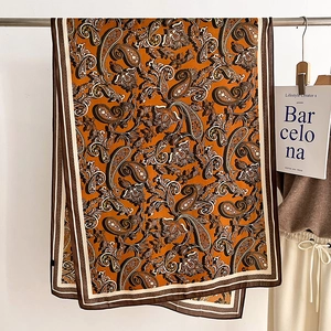 Detailed macro view of retro orange paisley print scarf with silky texture and striped edges