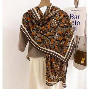 Retro paisley print oversized silk scarf in brown tones worn as a stylish shawl wrap