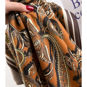 Close-up of paisley print scarf featuring orange and brown tones with herringbone texture