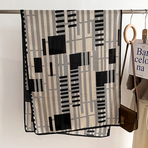 Close-up of black and white geometric scarf with checkered pattern on a hanger