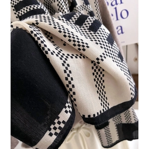Detailed view of thick black and white checkerboard knit scarf with textured herringbone weave