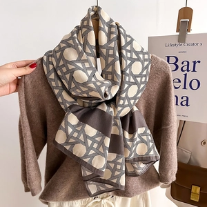 Chic beige and dark brown geometric grid scarf draped over dark knitwear for autumn