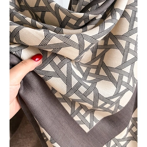 Detail of soft cream scarf with black stripes and grey herringbone woven edge texture