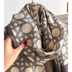 Beige winter scarf with black geometric grid pattern on a wooden hanger stylish accessory