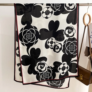 Detail of camellia flower print silk scarf with red contrast hem and smooth texture
