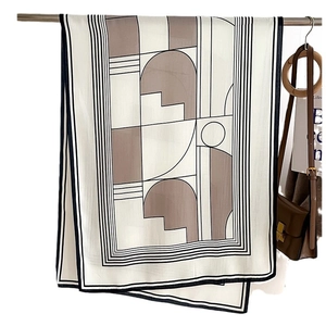 Modern geometric striped silk scarf in mocha brown and cream colors with a leather bag