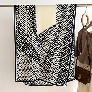 Close-up of black and white geometric G-pattern silk scarf with premium draping texture