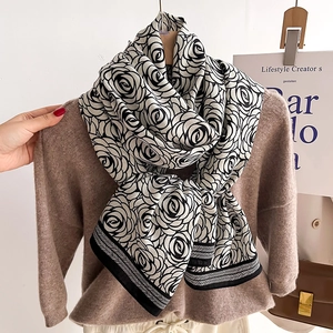 Elegant black and white camellia shawl with geometric striped edges draped on a sweater