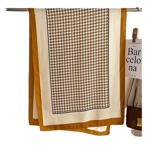 Eleganter Hahnentritt-Schal in Senfgelb und Braun aus seidigem Stoff an einem Kleiderbügel