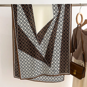 Detail of elegant geometric silk scarf in brown and black draped on a metal stand