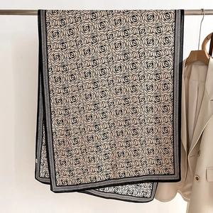 Detail showing elegant beige scarf with black floral patterns and refined textures
