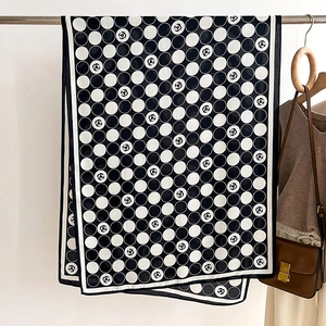 Detail of a large black and white polka dot scarf with camellia floral patterns and piping
