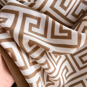 Detailed close-up of brown and beige geometric pattern on soft knitted scarf fabric
