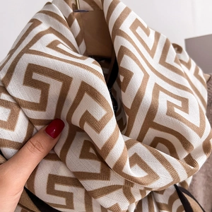 Macro shot of high-density knit scarf featuring brown geometric maze pattern and soft texture