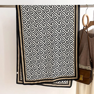 Detail of classic geometric Greek key pattern scarf with khaki contrast trim hanging