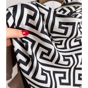 Close-up of woven black and white geometric meander pattern on a soft winter shawl scarf